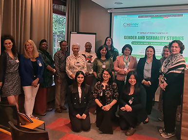 The image appears to show a group of people gathered in a room, posing together for a photograph. The setting seems to be a professional or academic environment, possibly a conference or workshop. There is a screen in the background displaying a presentation slide with the title "Gender and Sexuality Studies," indicating that the event may be related to these topics.