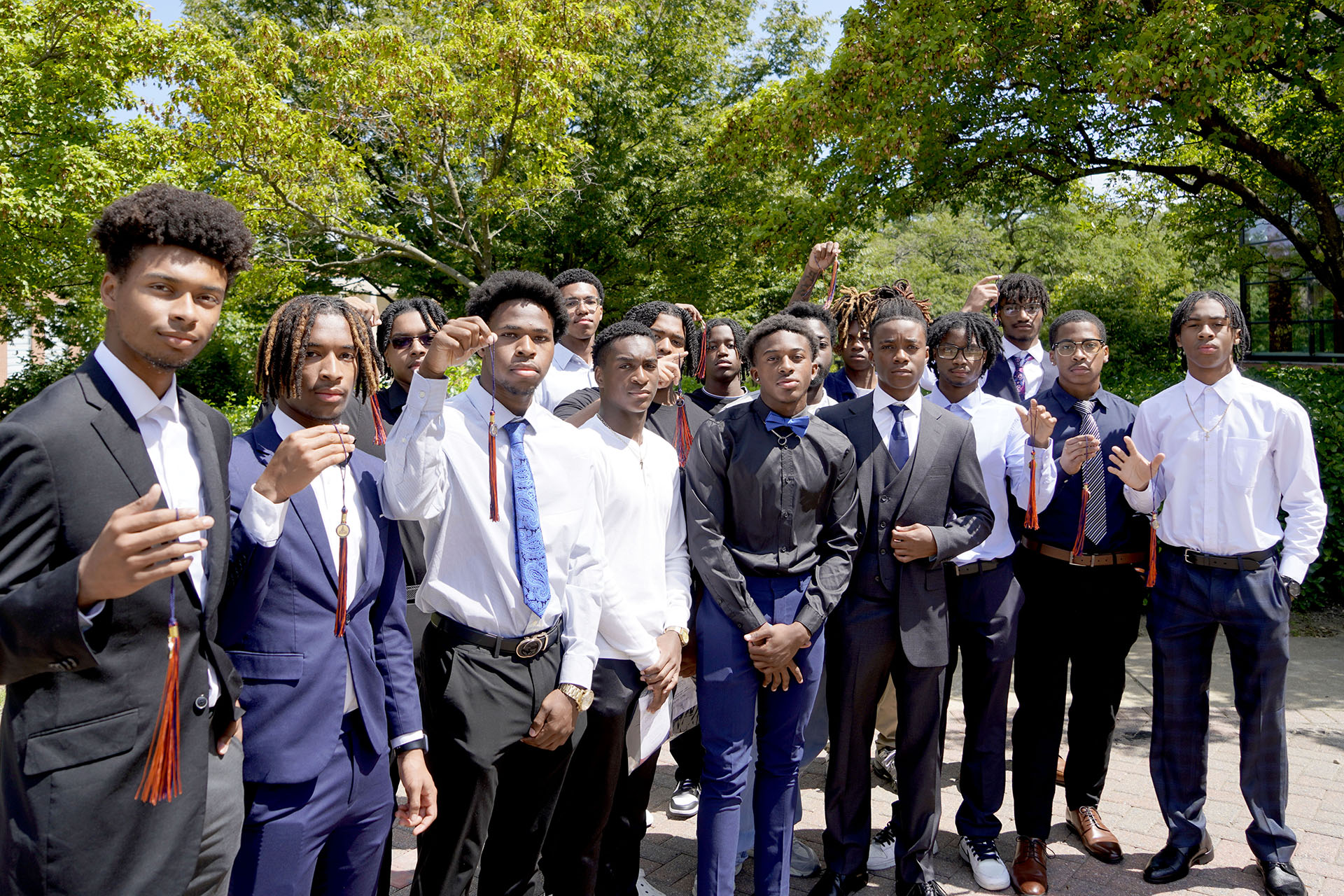 group of male students holding graduation tassels